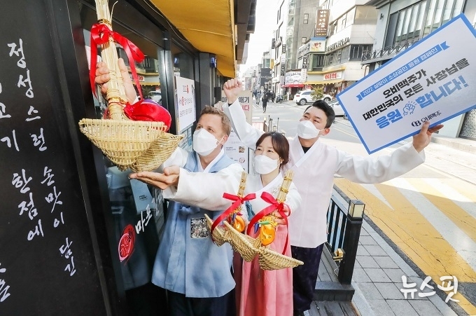 한복을 입은 오비맥주 배하준 대표(왼쪽)와 직원들이 강남구 삼성동 인근 음식점 입구에서 복조리를 달고 있다. / 사진=오비맥주 제공