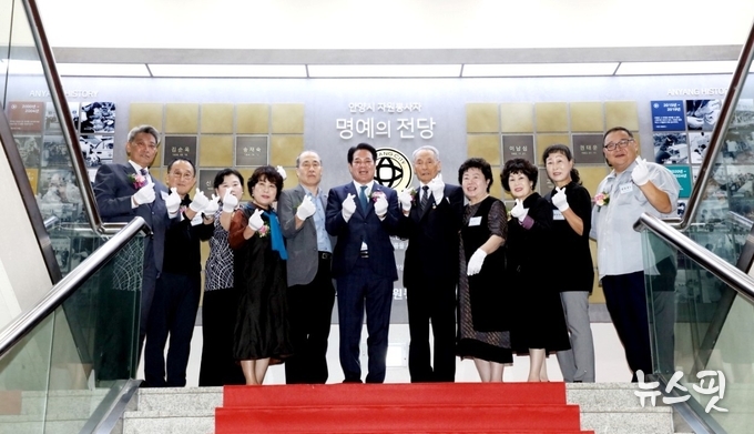 자원봉사자 명예의 전당 앞에 선 최대호 안양시장(가운데)과 10명의 등재 봉사자.(사진=안양시)