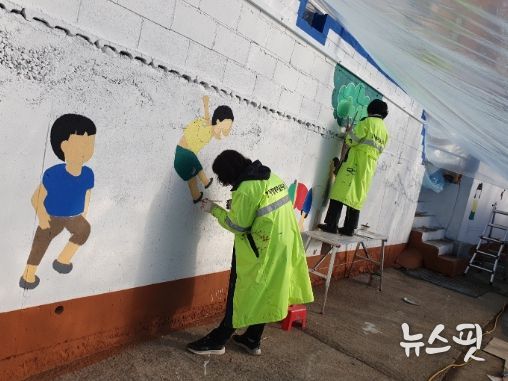 대곶면행복마을관리사무소에서 실시한 ‘벽화 그리기 사업’ 참여자들이 하얀 바탕의 벽에 벽화를 그려 넣고 있다.
