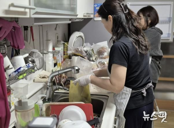 주방정리 매니저가 홀몸 어르신 가정을 방문해 냉장고와 주방을 정리하고 있다